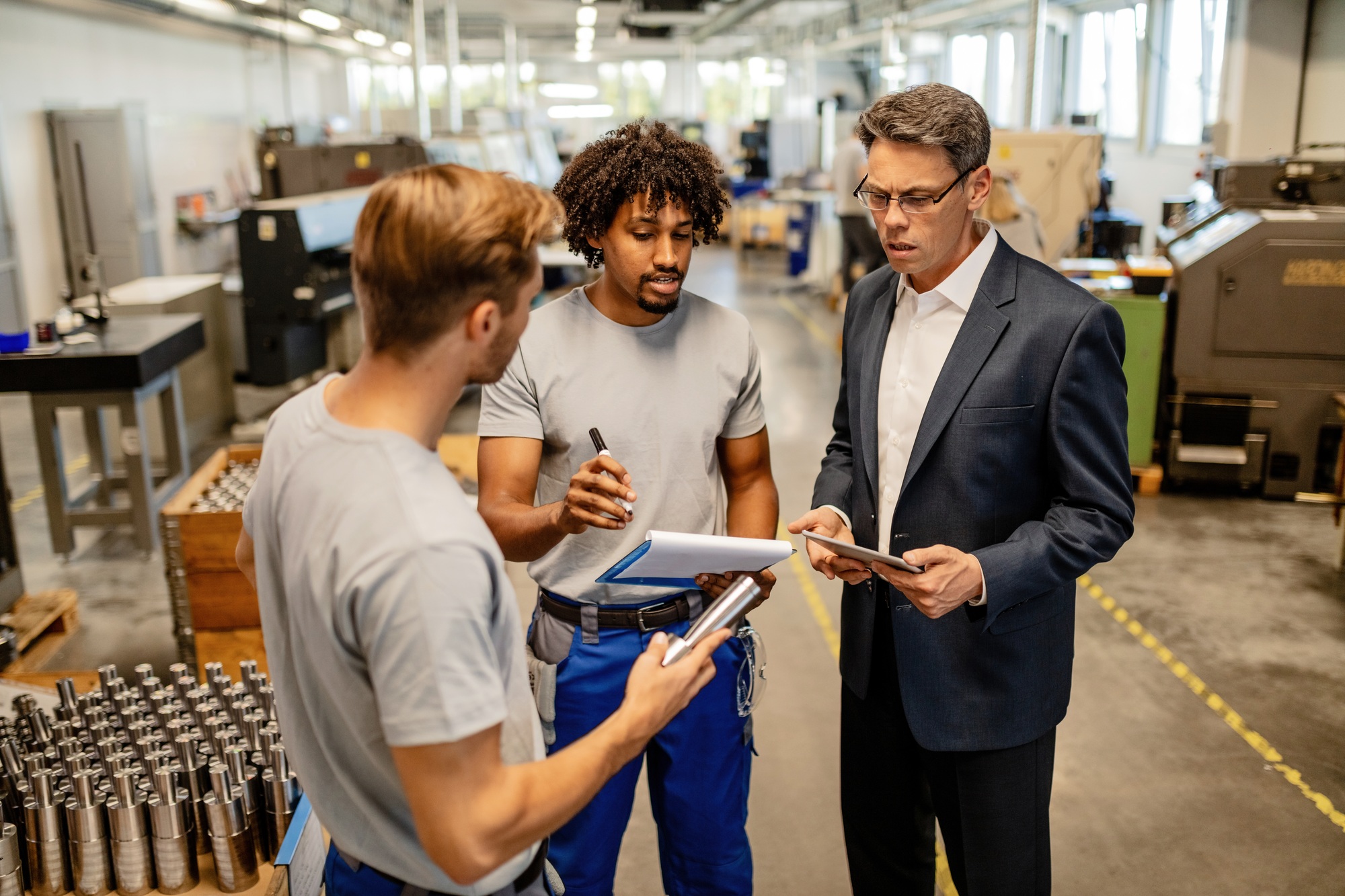 Mid adult engineer and metal workers doing product inspection in a factory. Mid adult engineer and metal workers doing product inspection in a factory.